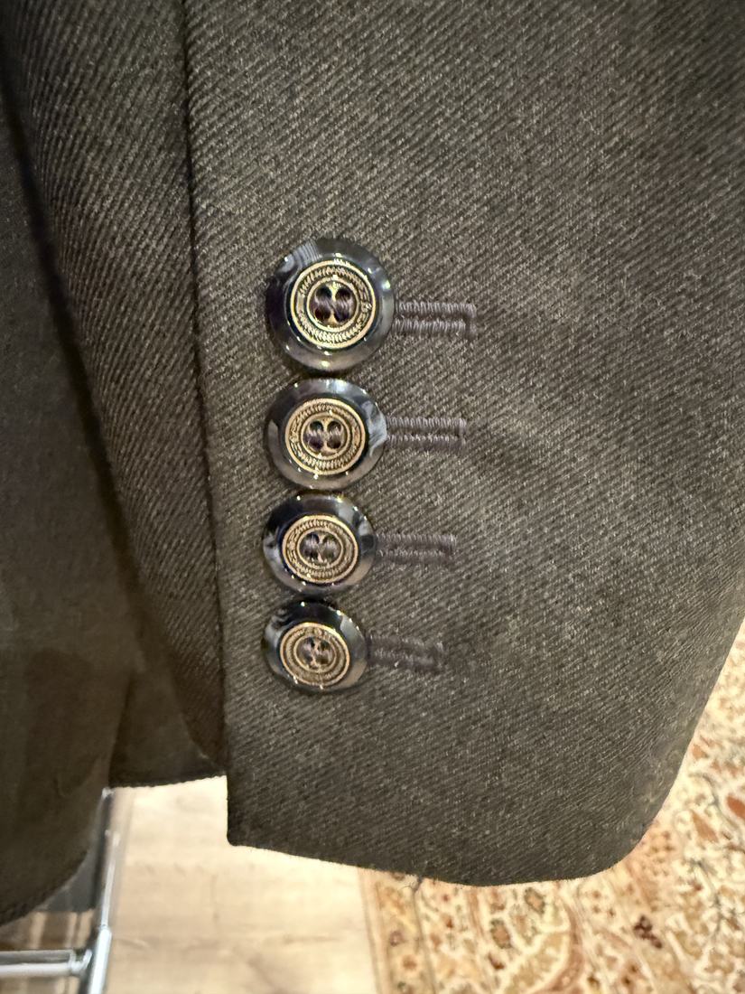Four dark buttons at the jacket cuff with worked buttonholes beside them.