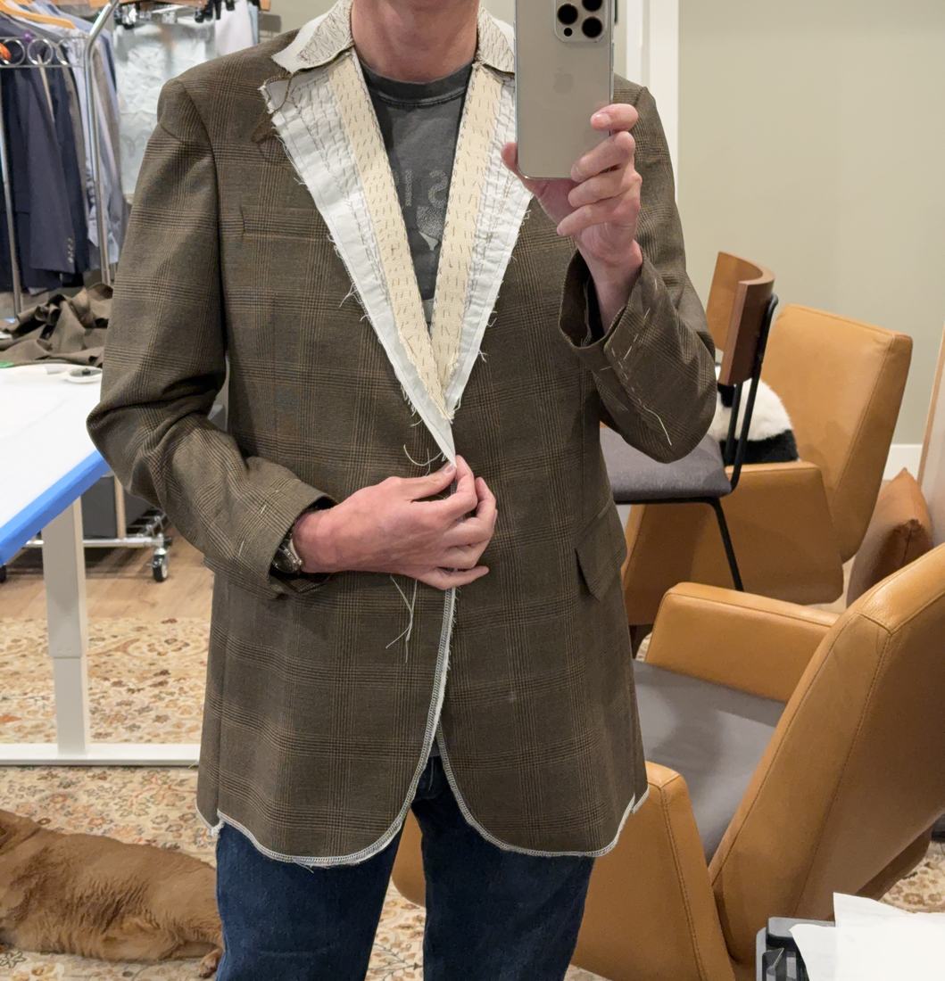 The glen plaid jacket shell worn for a fitting, with the canvas and tape still exposed along the lapel.